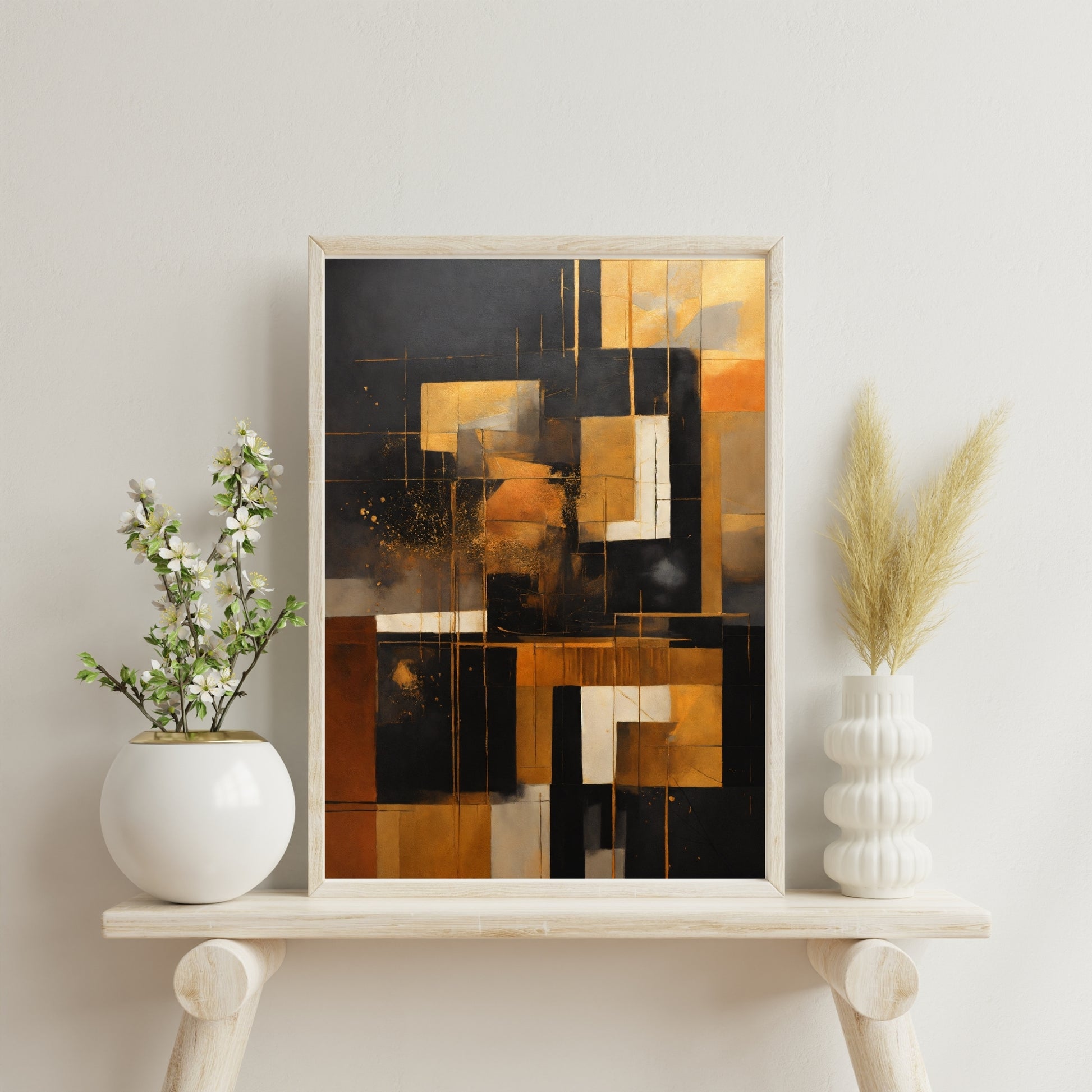 Abstract art print in gold, black, and neutral tones with a geometric design, framed and displayed on a stylish wooden shelf with modern decor.